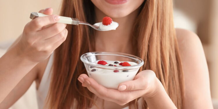 Young woman eating yogurt, closeup